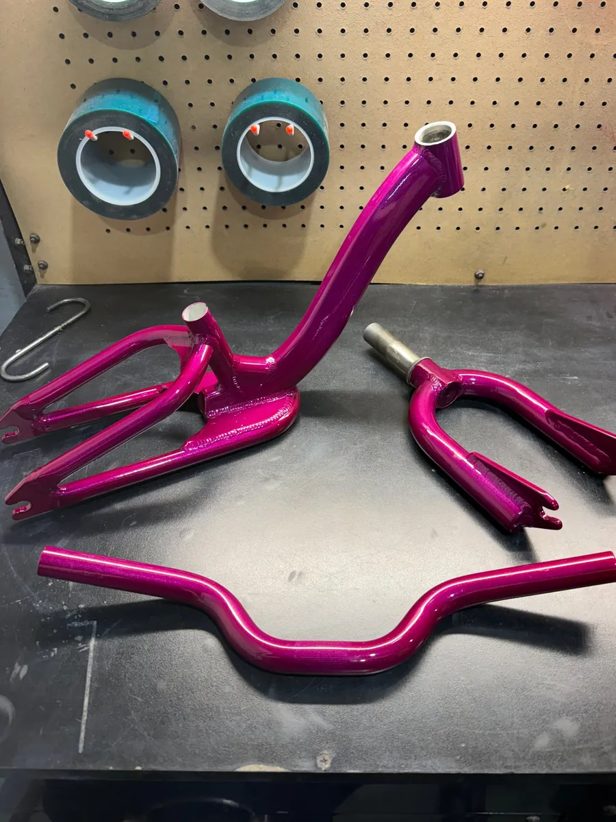 BMX bike frame, fork and handlebars powder coated metallic magenta, on the shop bench