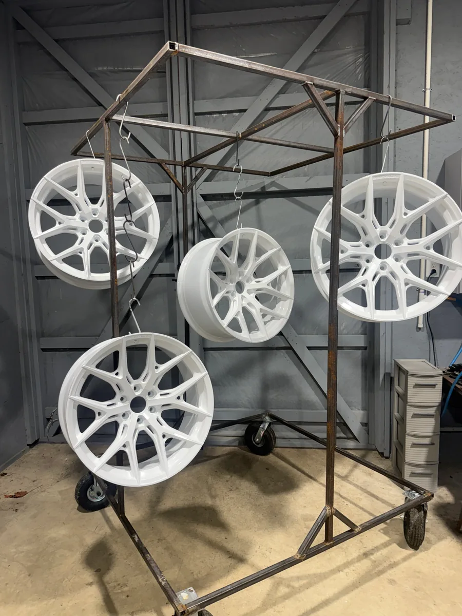 Set of four Vossen wheels powder coated gloss white, hanging on the shop rack